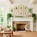 Bright summer living room fireplace mantel styled with lush green botanical art prints and trailing ivy.