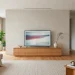 Clean modern living room featuring a low-profile minimalist wooden TV stand under a wall-mounted flat screen.