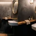 Wide view of a modern tiny powder room featuring a smart corner sink and warm brass fixtures.