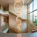 Luxury statement chandelier hanging in a modern double-height staircase void with glass railings and natural light.
