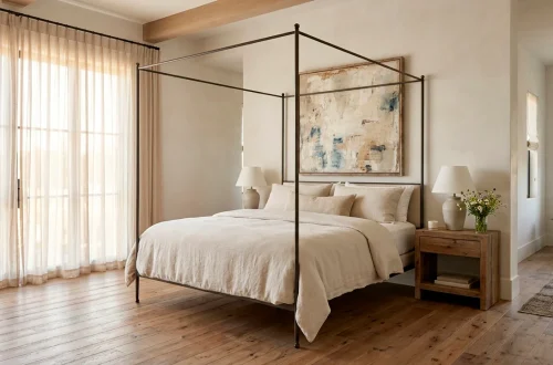 A modern French Country bedroom featuring an iron canopy bed, linen bedding, and limewashed walls.