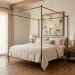 A modern French Country bedroom featuring an iron canopy bed, linen bedding, and limewashed walls.