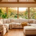 Cozy sunroom with a plush cream modular sectional sofa and large windows