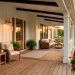 Modern farmhouse porch featuring warm wood decking, white columns, and cozy rattan furniture at golden hour