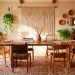 A relaxed global-inspired boho dining room featuring a raw wood table, mismatched chairs, and lush indoor plants.