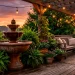 A stunning rustic patio setting featuring a large earthy terracotta water fountain surrounded by ferns and string lights.
