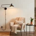 Cozy apartment corner featuring a stylish matte black plug-in wall sconce over a beige accent chair