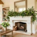Beautifully styled spring fireplace mantel decorated with lush greenery garlands in a bright living room.