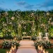 Wide view of an elegant wedding stage featuring a lush greenery wall with ferns and white roses.