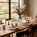 Minimalist Japandi Thanksgiving table setting with a clear glass vase centerpiece and dried branches