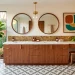 Wide view of a mid-century modern bathroom with a warm walnut vanity and brass fixtures