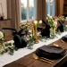 Modern elegant Easter table setting featuring matte black ceramic rabbit figurines, white linen, and gold cutlery.