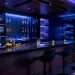 Modern home bar with smart tech lighting and automated cocktail dispenser on a black marble counter.