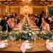 Wide view of an elegant wedding reception table featuring intricately folded blush pink napkins on gold charger plates.