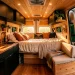 Wide view of a beautiful camper van interior showcasing clever space saving design and warm wood paneling.