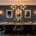 Sophisticated dining room featuring charcoal grey picture frame wall molding, wooden table, and brass chandelier