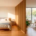 A modern wooden slat room divider separating a bedroom and living room in a small, sunlit studio apartment.