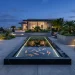 Wide horizontal view of a modern geometric fish pond on a contemporary terrace with koi and LED lighting.