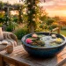 Beautiful ceramic tabletop water garden with floating lilies and a bamboo spout on a sunny outdoor patio.