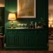 Luxurious emerald green home bar station with gold hardware and crystal glassware in a moody living room
