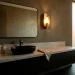 Luxurious powder room interior featuring dark moody walls, a glowing brass sconce, and an elegant vanity setup.