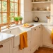 Bright sunlit kitchen featuring vibrant marigold yellow dish towels hanging on a white farmhouse sink and oven handle.