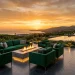 Luxury outdoor patio featuring emerald green furniture, planter pots, and a glowing fire table at sunset