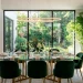 Modern dining room featuring a sleek polished glass table with gold metallic accents and lush indoor plants.