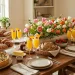 Elegant Mother's Day brunch table setting with quiche, mimosas, fresh pastries, and beautiful spring tulips in a sunlit room.
