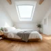 Bright white modern attic bedroom with skylights and low profile furniture