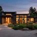 Modern home exterior featuring dark moody board and batten siding at dusk with warm lighting.