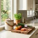 Elegant ceramic countertop compost bin sitting on a modern sunlit kitchen counter next to fresh vegetables.