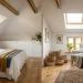 Beautifully renovated attic featuring white sloped ceilings, built-in storage cabinets, and warm sunlight.