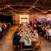 Chic industrial urban loft wedding reception showcasing exposed brick, long wooden tables, and warm ambient string lights.