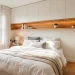 Wide view of a tiny bedroom using clever over-bed storage cabinets and shelves to maximize space