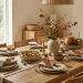 Japandi Thanksgiving tablescape featuring matte ceramic plates, organic bowls, and autumn foliage.