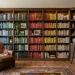 Wide view of a stunning color coded home library in a cozy living room with rainbow organized bookshelves.