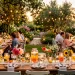 A wide view of a summer patio table decorated with various upcycled mason jar centerpieces under string lights.