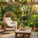 Luxurious outdoor patio featuring a cozy hanging rattan egg chair with white cushions