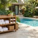 Chic poolside organizer holding rolled towels and sunscreen next to a bright blue backyard pool