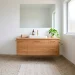 Small modern bathroom featuring large format terrazzo tiles, a floating oak vanity, and brass hardware in a minimalist layout.