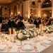 Luxurious formal wedding table setting with gold chargers and crystal glasses under warm candlelight