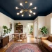 A wide view of a beautifully decorated narrow room featuring a bold dark painted ceiling and statement lighting.