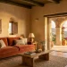 Mediterranean living room featuring textured ochre walls and a burnt siena velvet sofa bathed in sunlight