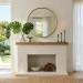 A wide view of a bright minimalist summer living room featuring a beautifully styled white fireplace mantel.