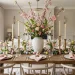 Elegant Easter tablescape featuring tall spring branches and symmetrical place settings in a sunlit dining room.