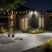 Bright outdoor lighting illuminating a modern backyard workout space with kettlebells and a yoga mat at night.