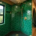 Wide view of a luxury camper van interior featuring an emerald green hexagon tiled shower with brass fixtures.
