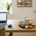 Stylish modern home office desk showing a vibrant punch needle coaster holding a ceramic coffee mug in natural light.