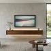 Minimalist modern living room with a glowing smart TV wall unit and hidden technology.